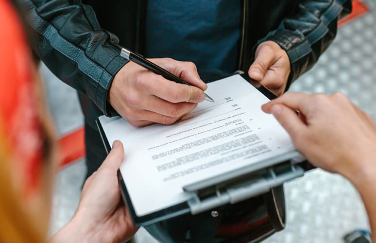 A man fills out paperwork on a black clipboard